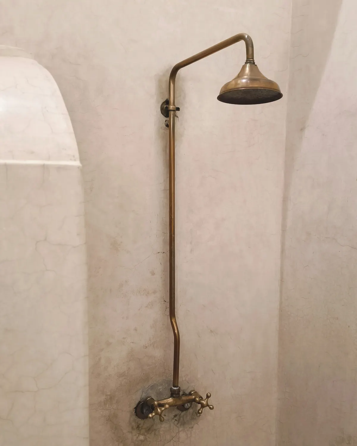 Douche met naadloze kalkwanden en een messing opbouwdouche