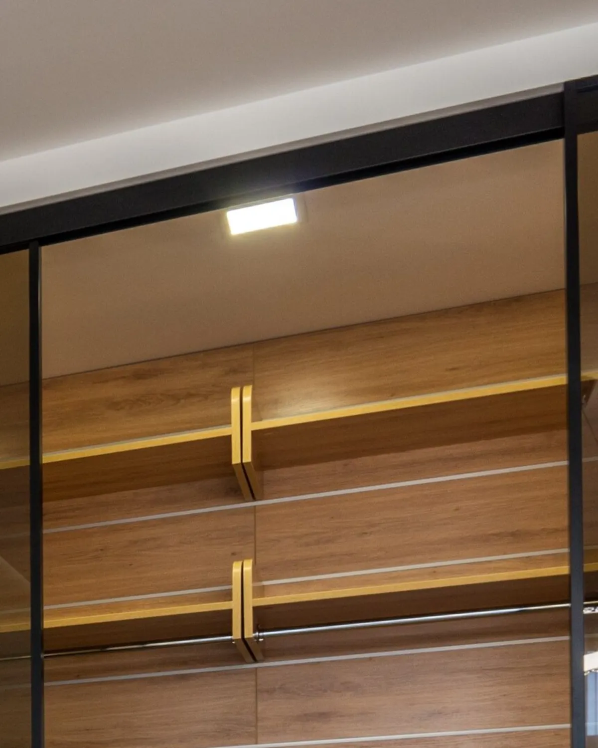 Inloopkast met schuifdeuren van bronsgetint glas voor houten planken