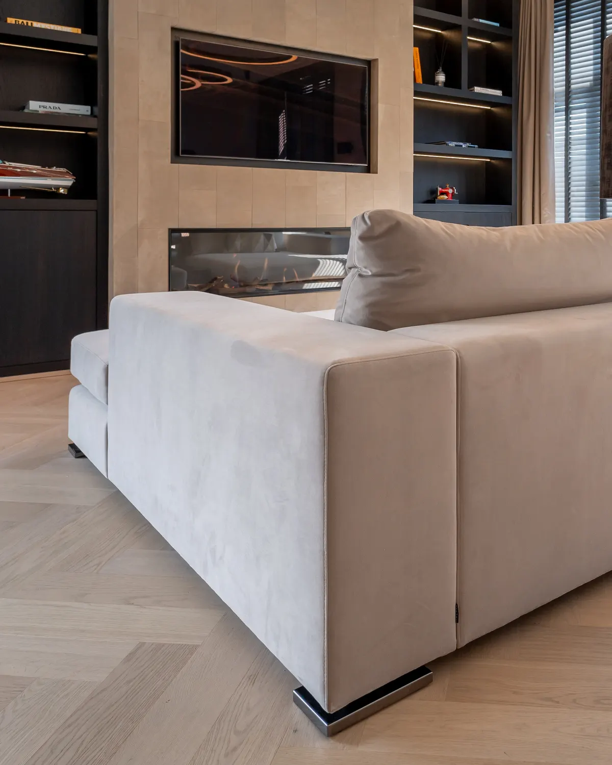 Lichte eiken visgraatvloer in een woonkamer met een beige bank en donkere maatwerkkasten